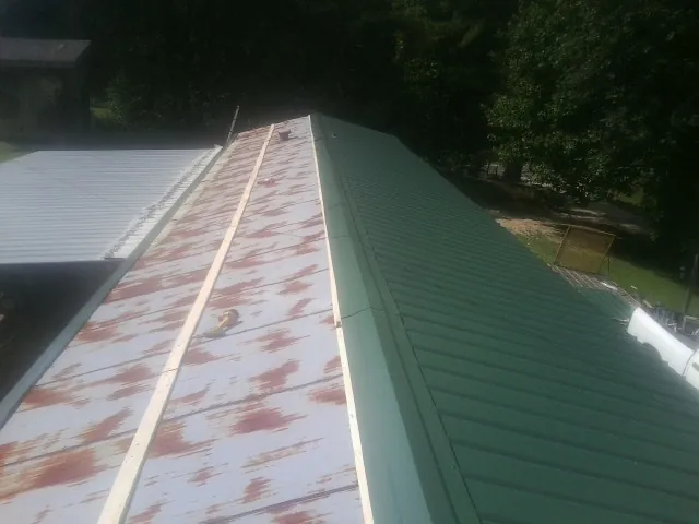 Old rusted panels beside newly installed green metal roofing — Wind Damage Roof Repair by Roofing Brothers in Dillonvale
