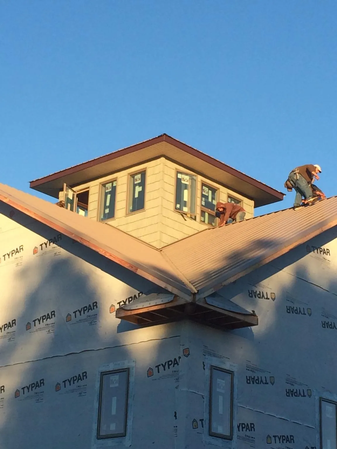 Roofers working around a rooftop cupola on a new metal roof at sunset — Roof Waterproofing in Dillonvale by Roofing Brothers
